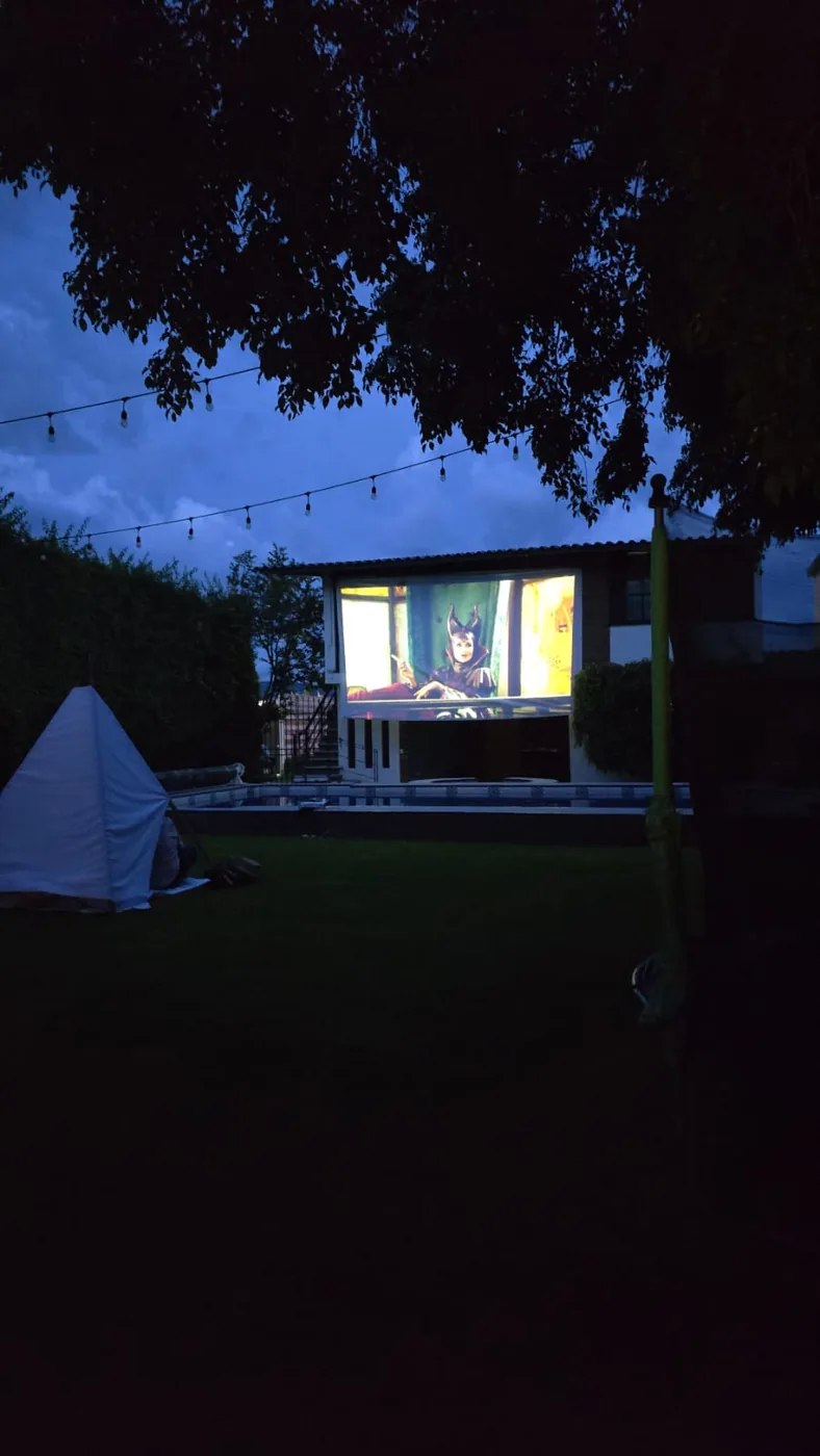 Película proyectada en la pantalla gigante al atardecer, junto a la alberca — Godettia