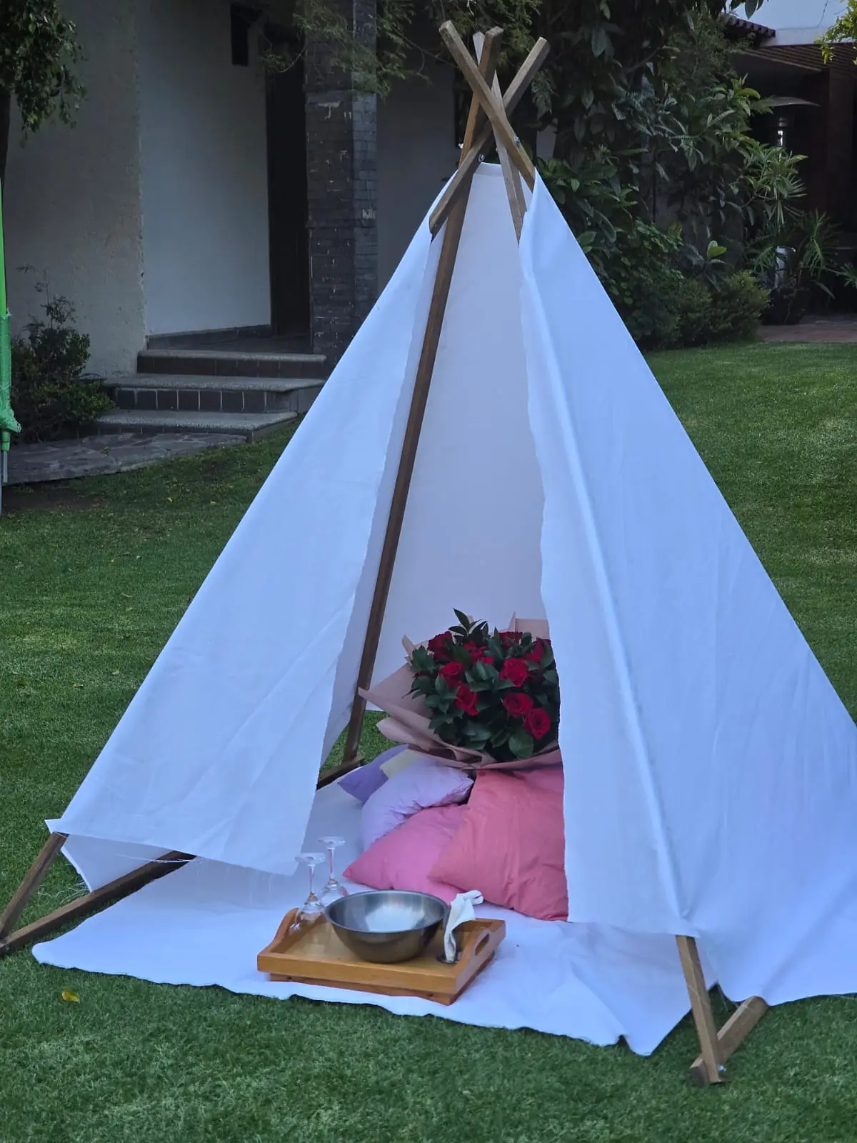 El teepee con ramo de rosas, cojines rosas y charola lista antes de que lleguen
